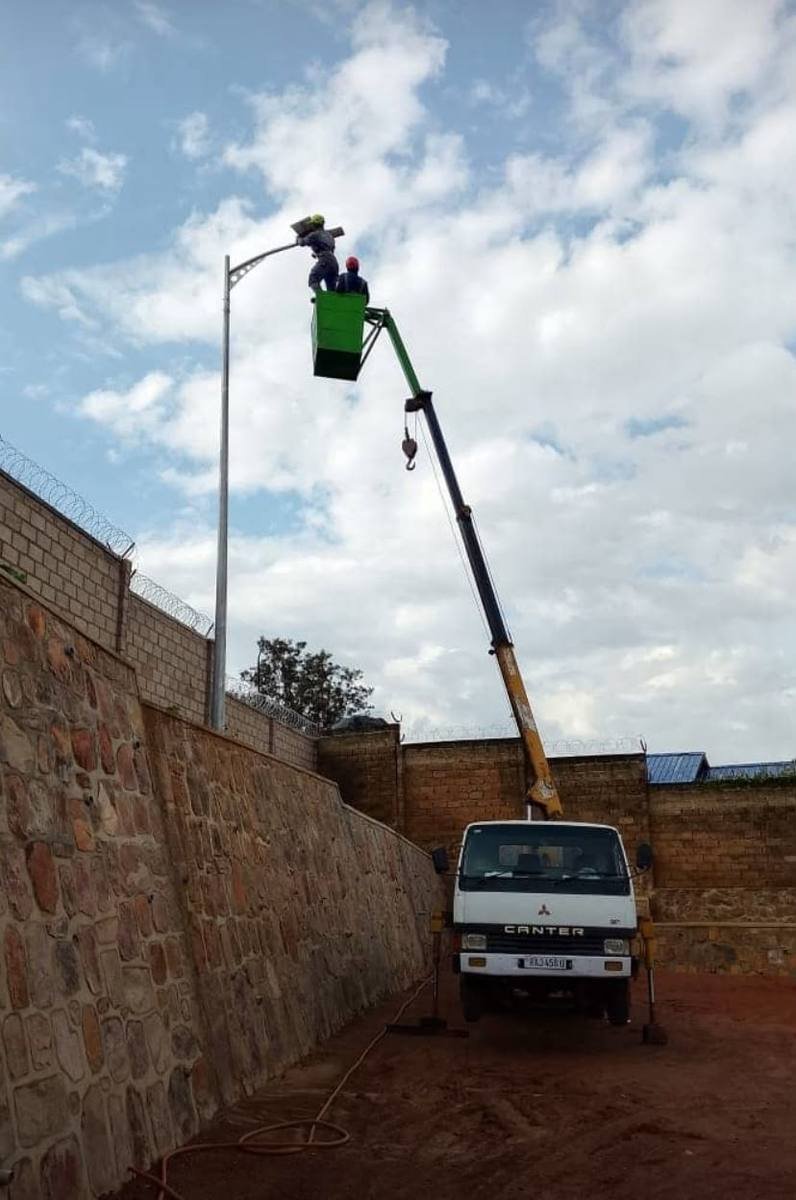 Megira crane truck lifting workers in a bucket to service a streetlight